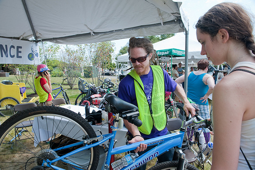 A volunteer helps a cyclist at the Bike Maintenance tent.